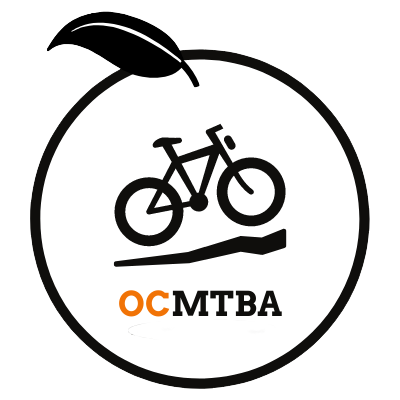 OCMTBA logo - a drawing of an orange with a bike and the initials OCMTBA inside.